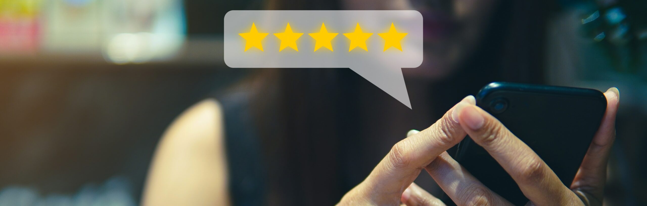 A person holding a cell phone with a bubble of a 5-star rating in front of it